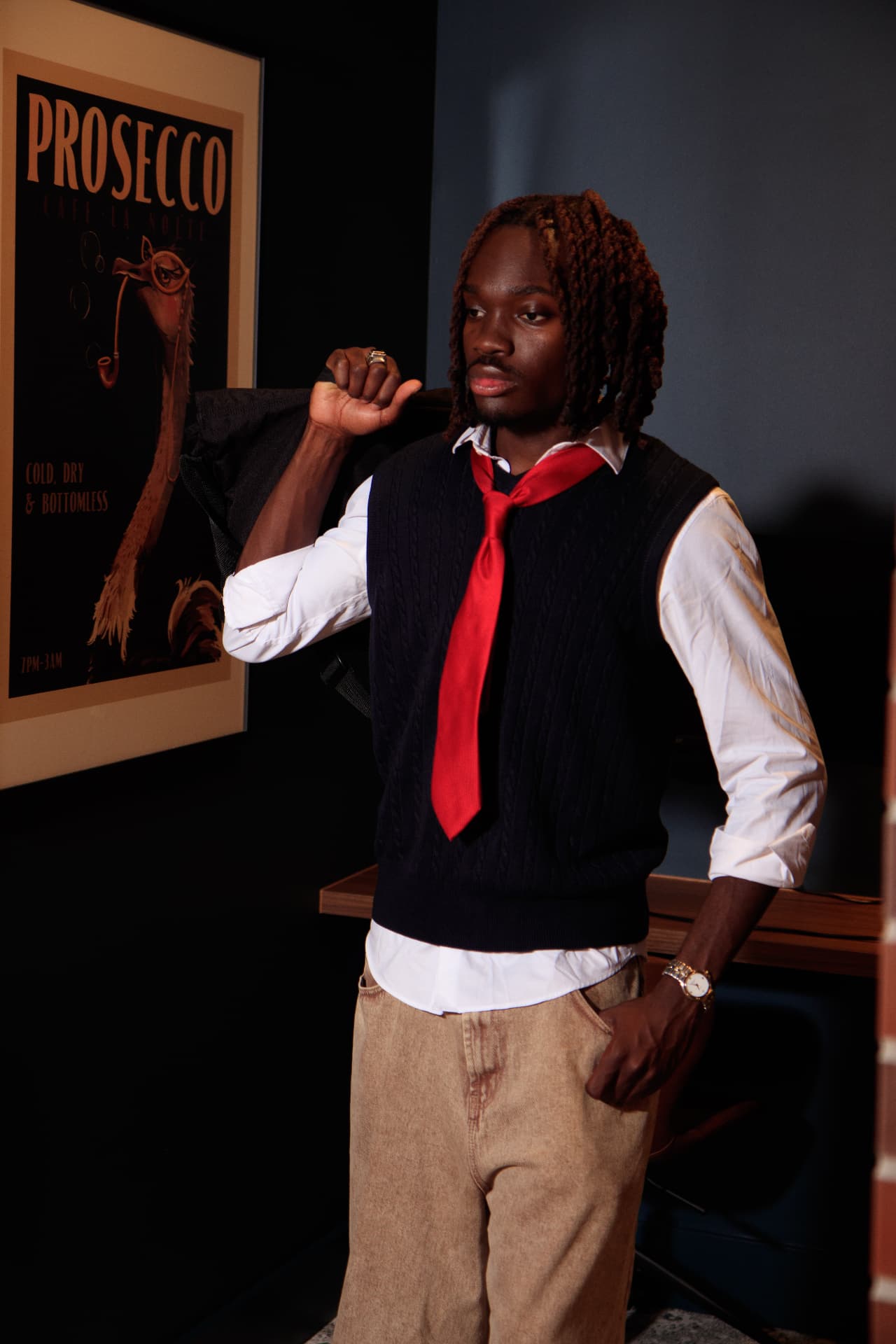 Portrait of a young man in a white shirt, navy sweater vest and red tie