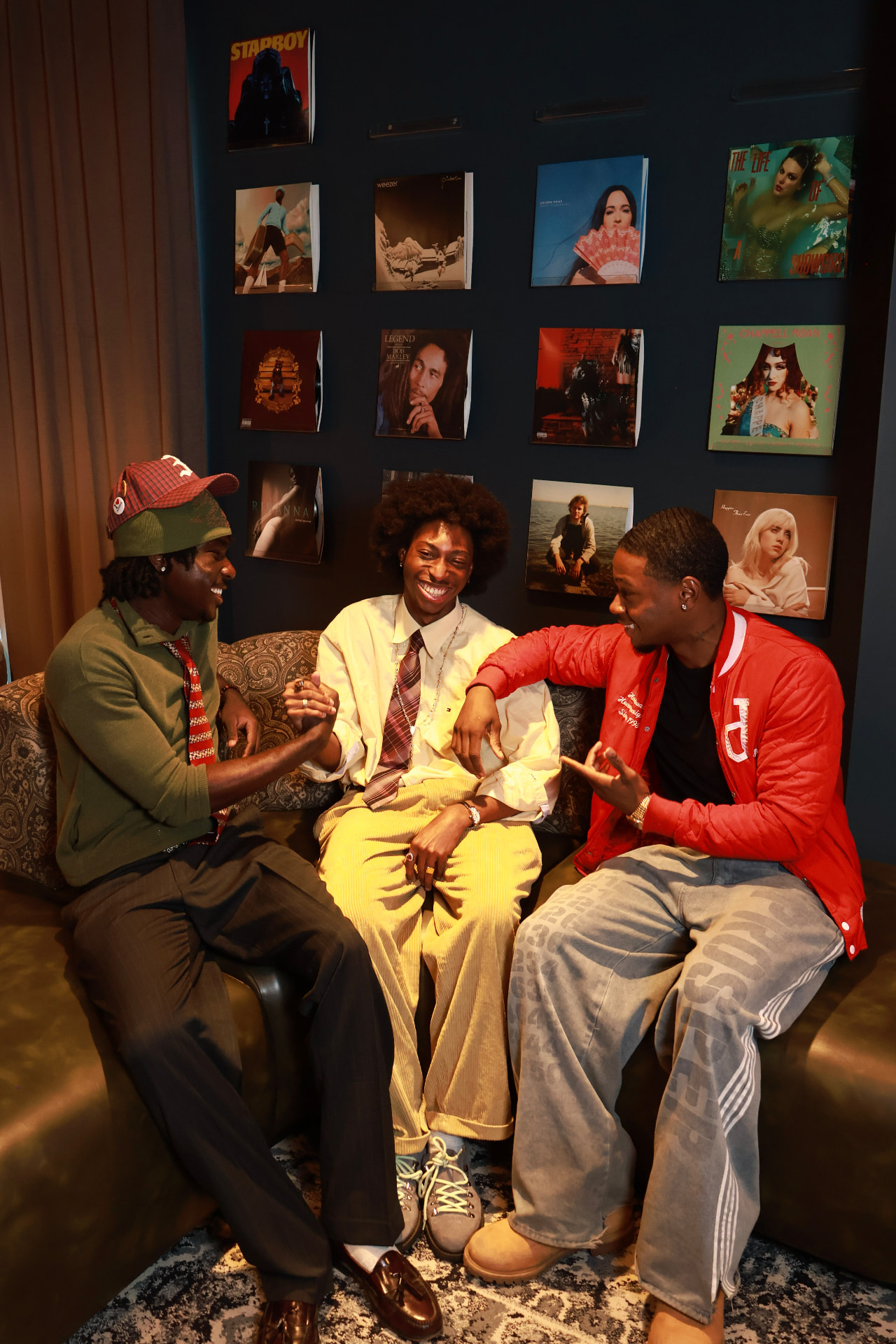 Three friends sitting together on a sofa in front of a wall of vinyl records at an OREWA gathering